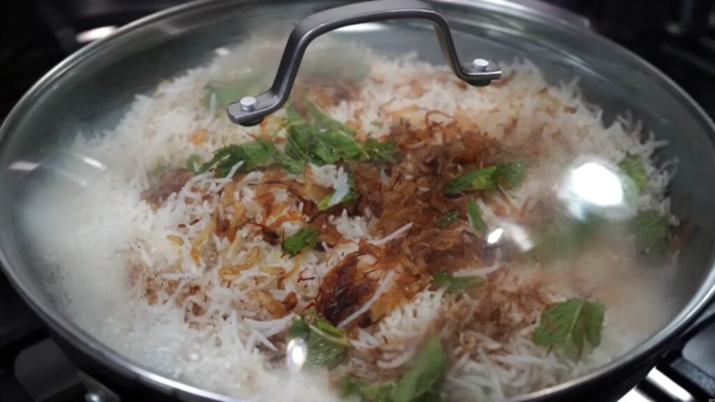 Close-up of gluten-free mutton biryani in a pan, showcasing golden brown fried onions and fragrant coriander top tender meat and Gluten-Free Mutton White biryani |Classic authentic basmati rice.