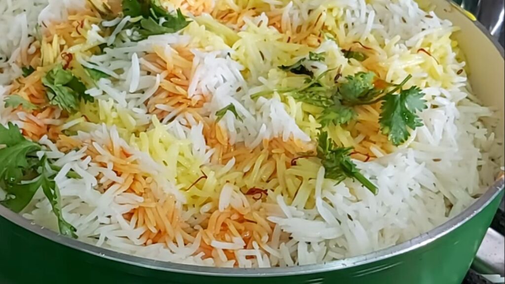Gluten-Free Chicken Biryani | A Simple Twist on a Classic 10 Basmati rice layered in a green pan, garnished with coriander and saffron strands, ready to simmer on low heat for fragrant flavors."