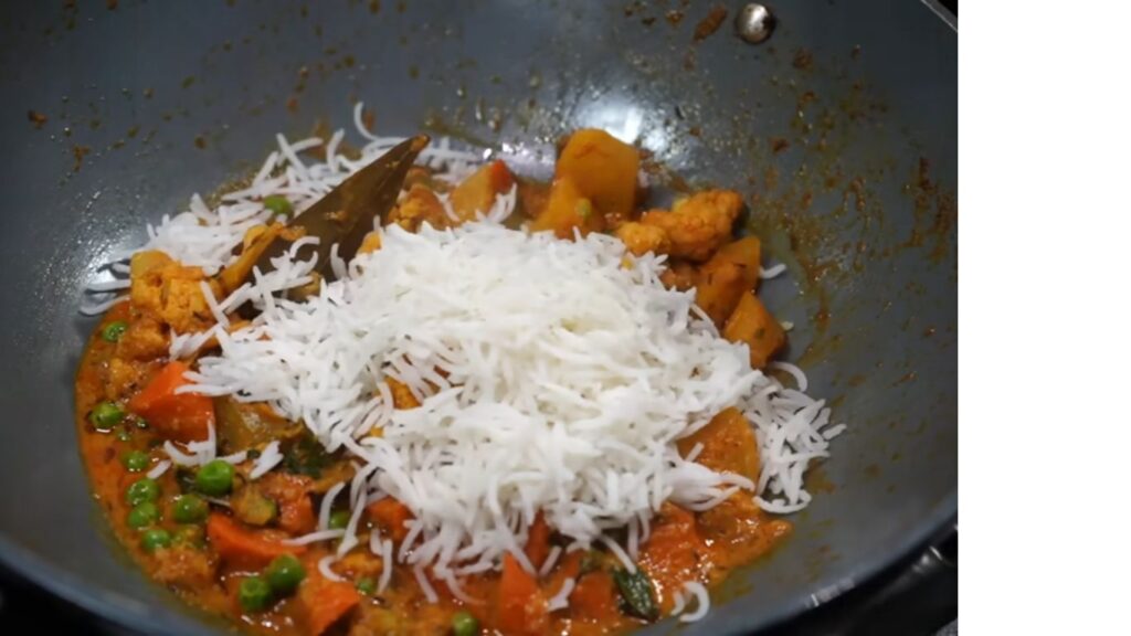 Colorful Gluten-Free Vegetable Biryani | Light and Healthy 8 A deep pot showing layers of cooked vegetable mix topped with half-cooked basmati rice, sprinkled with fresh coriander and mint leaves. Colorful Gluten-Free Vegetable Biryani | Light and healthy