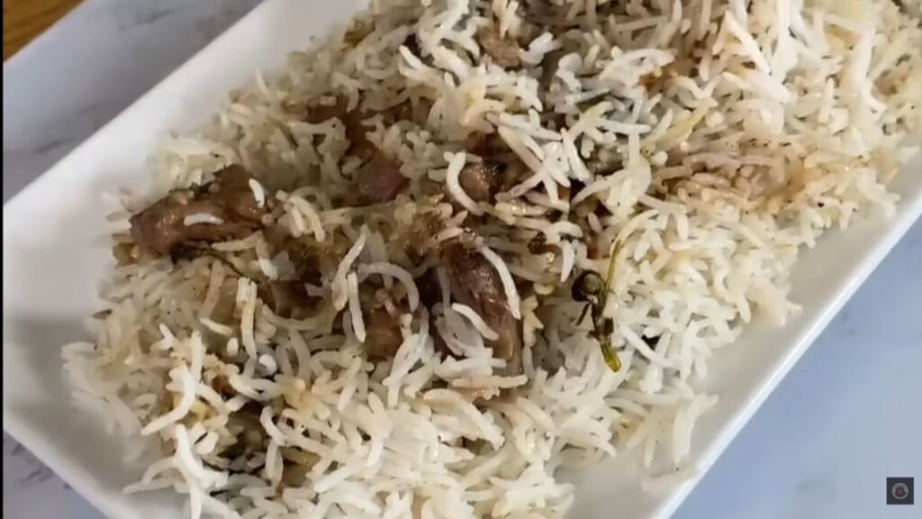 A hot plate of gluten-free white mutton biryani served with raita, highlighting succulent lamb pieces and rich gravy layered with spiced Gluten-Free Mutton White biryani |Classic authenticrice."