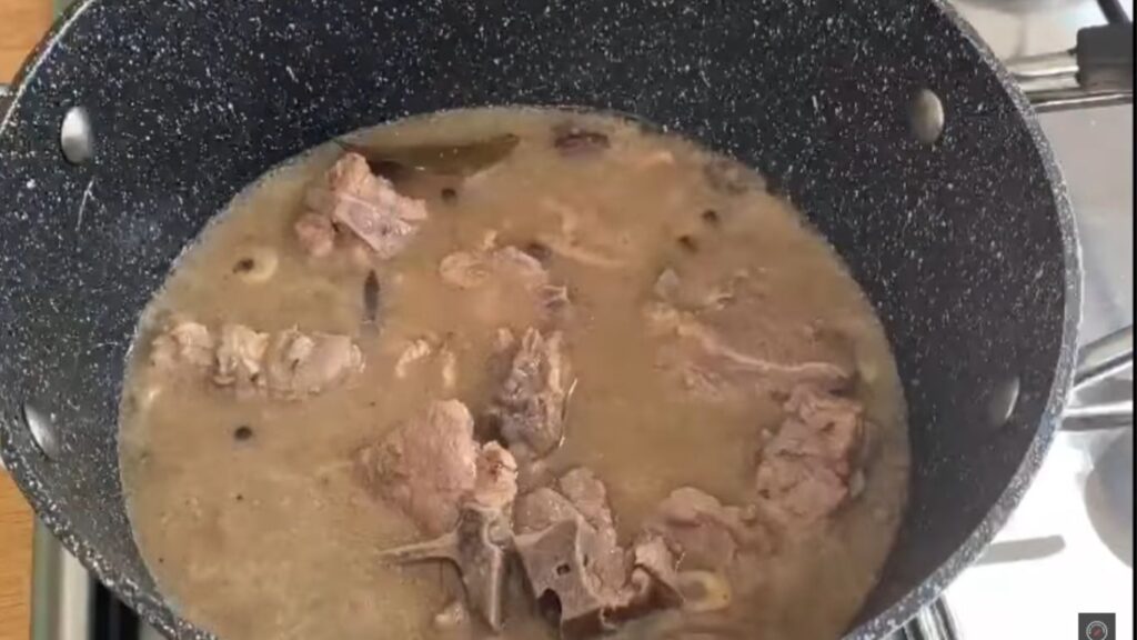 Mutton simmering in a pan with golden brown onions, tomatoes, and biryani masala, creating a thick gravy with cumin seeds adding flavor on medium heat. Gluten-Free Mutton White biryani |Classic authentic